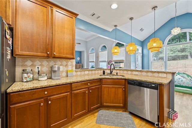 kitchen featuring lofted ceiling, kitchen peninsula, sink, appliances with stainless steel finishes, and light stone countertops