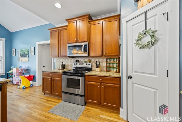 kitchen featuring light hardwood / wood-style floors, light stone counters, backsplash, and stainless steel appliances