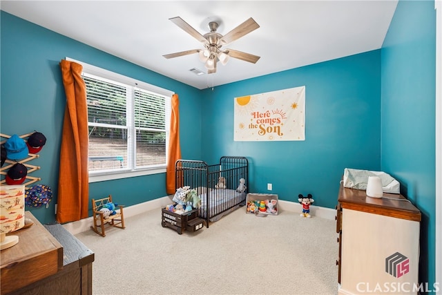 bedroom with carpet, ceiling fan, and a crib