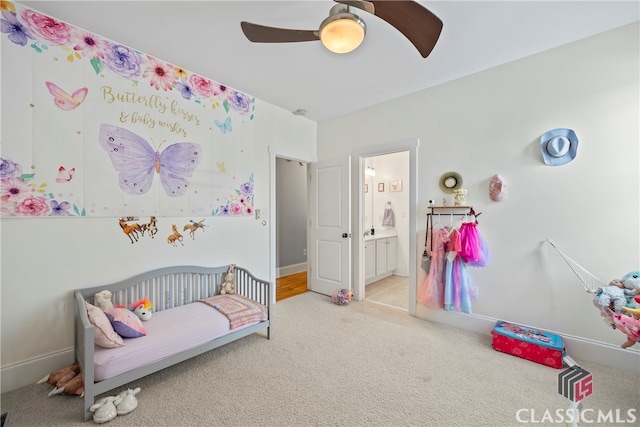 carpeted bedroom featuring ceiling fan, connected bathroom, and a nursery area