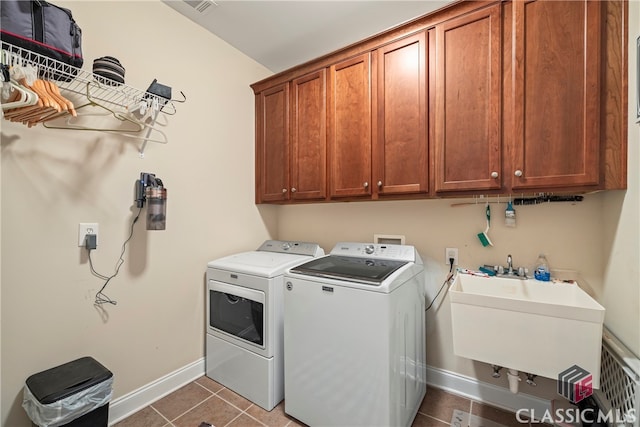 clothes washing area featuring washing machine and dryer, cabinets, dark tile patterned flooring, and sink