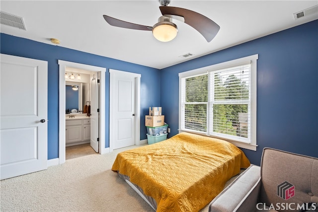 bedroom featuring ceiling fan, ensuite bath, and light colored carpet