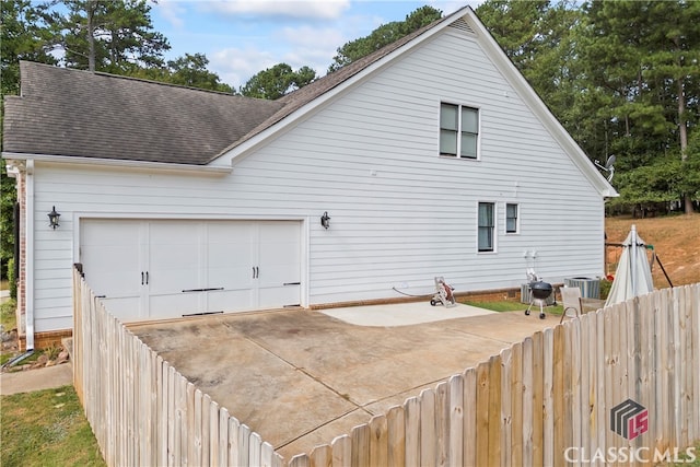 view of side of property featuring a garage and cooling unit