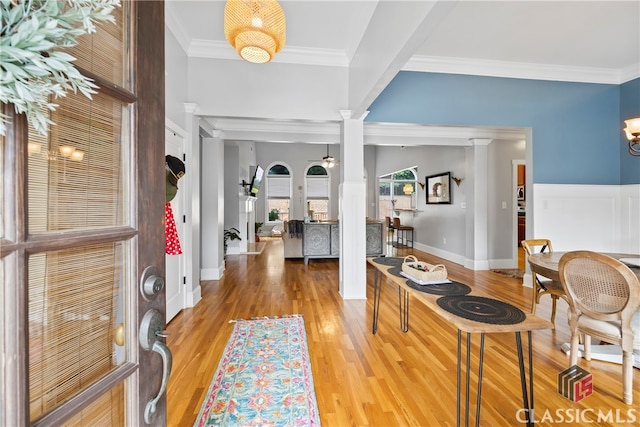 entrance foyer with decorative columns, crown molding, and light wood-type flooring