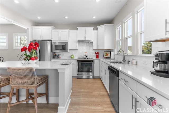 kitchen with sink, white cabinetry, plenty of natural light, a breakfast bar area, and stainless steel appliances