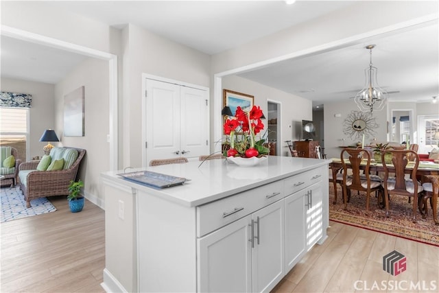 kitchen featuring white cabinetry, hanging light fixtures, light hardwood / wood-style flooring, and a kitchen island