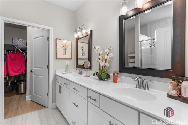 bathroom with a shower with shower door and vanity