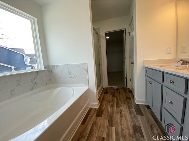 bathroom featuring hardwood / wood-style floors, vanity, and plus walk in shower