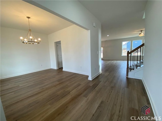 spare room with dark hardwood / wood-style flooring and ceiling fan with notable chandelier