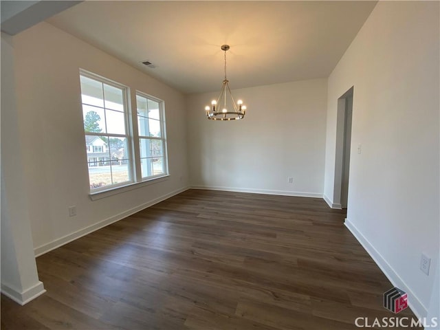 unfurnished dining area featuring dark wood-type flooring and an inviting chandelier