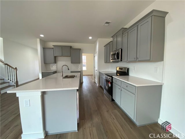 kitchen featuring sink, appliances with stainless steel finishes, a center island with sink, and gray cabinetry