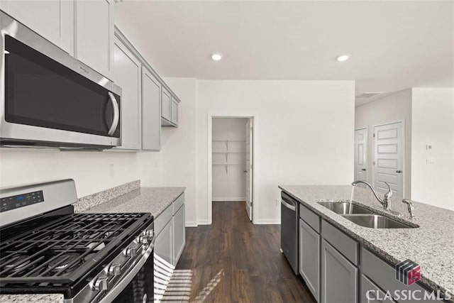 kitchen with light stone countertops, appliances with stainless steel finishes, sink, dark hardwood / wood-style floors, and gray cabinetry