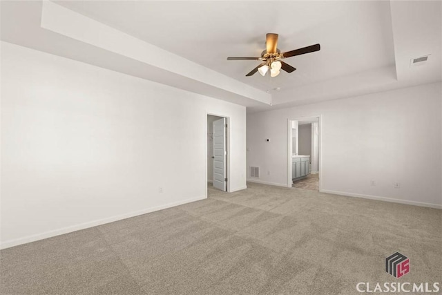 spare room with light carpet, ceiling fan, and a tray ceiling