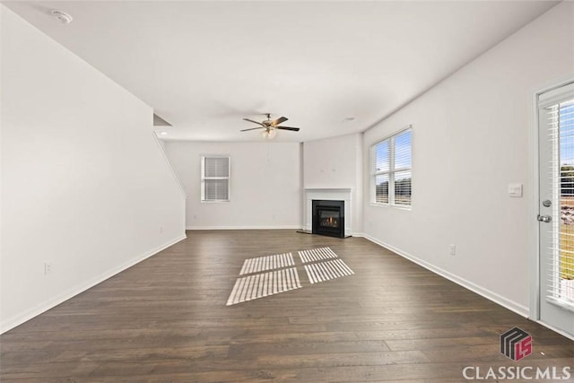 unfurnished living room featuring dark wood-type flooring, a wealth of natural light, and ceiling fan