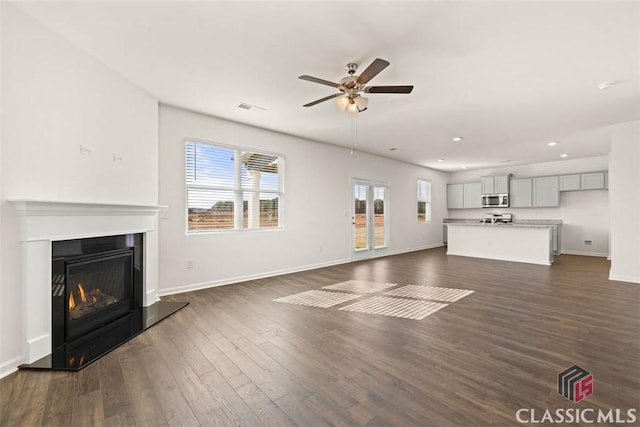 unfurnished living room featuring ceiling fan and dark wood-type flooring