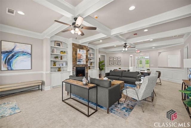 living room with ceiling fan, a fireplace, beam ceiling, built in features, and ornamental molding