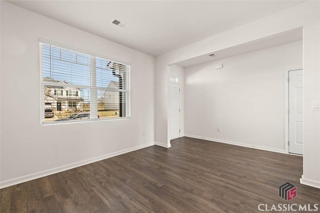 empty room with dark wood-type flooring and a healthy amount of sunlight