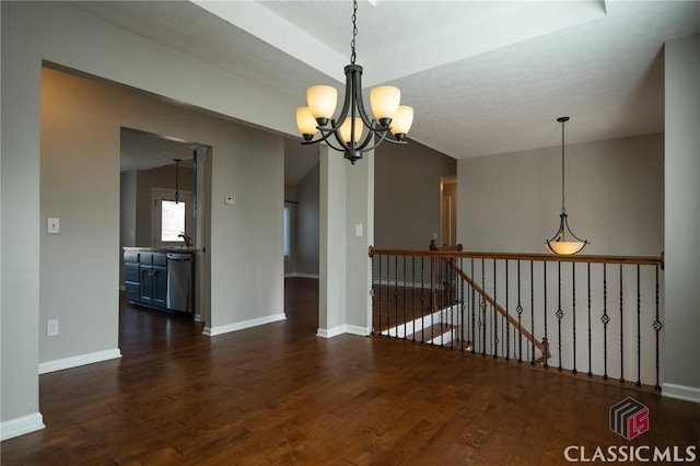 unfurnished room with lofted ceiling, dark wood-type flooring, and an inviting chandelier