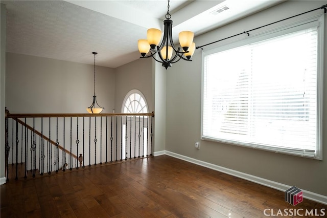 empty room featuring dark wood-type flooring and an inviting chandelier