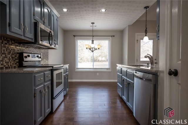 kitchen with a textured ceiling, appliances with stainless steel finishes, pendant lighting, and sink