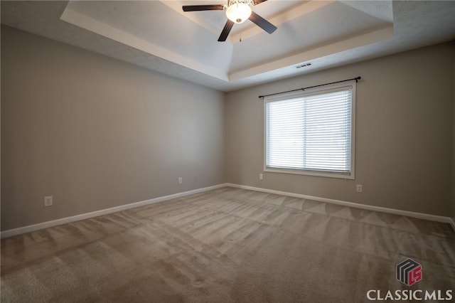 carpeted empty room with a raised ceiling and ceiling fan