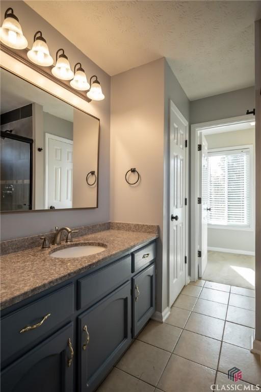 bathroom with a textured ceiling, vanity, and tile patterned flooring