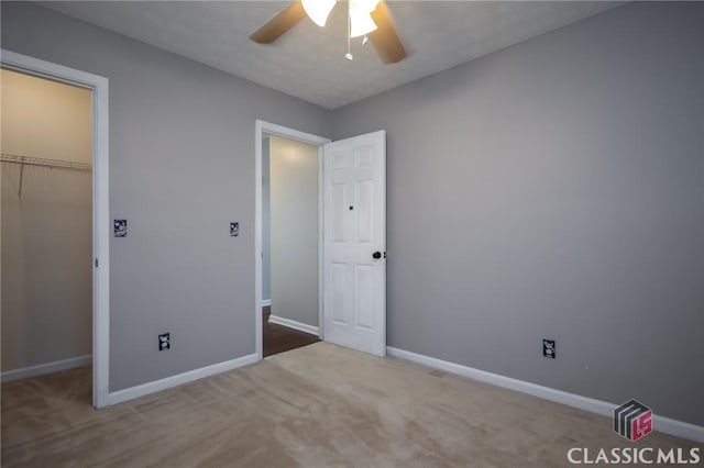 unfurnished bedroom with a spacious closet, a closet, ceiling fan, and carpet flooring