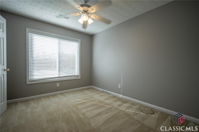 spare room featuring light carpet, ceiling fan, and a textured ceiling