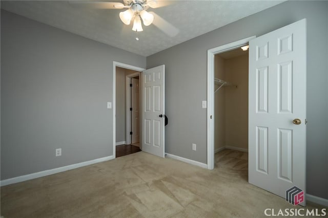 unfurnished bedroom with a spacious closet, light carpet, ceiling fan, a closet, and a textured ceiling