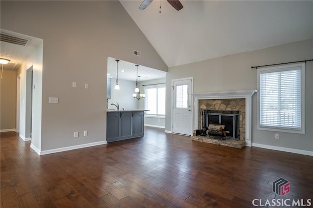 unfurnished living room with dark wood-type flooring, a fireplace, sink, high vaulted ceiling, and ceiling fan