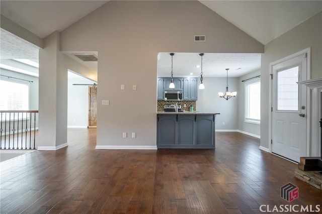 kitchen with dark hardwood / wood-style flooring, lofted ceiling, tasteful backsplash, and pendant lighting