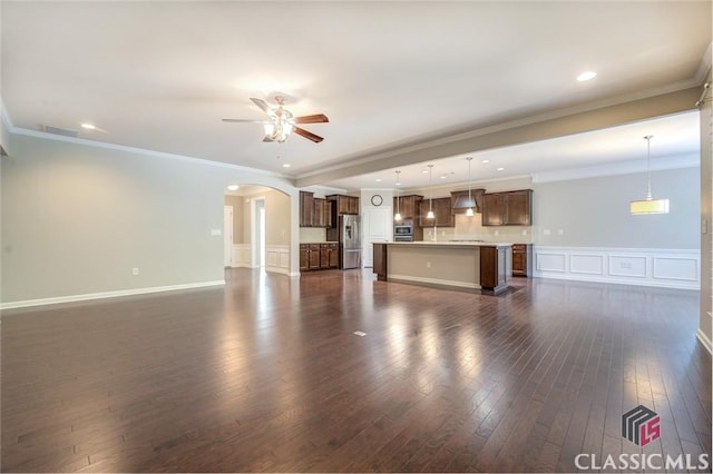 unfurnished living room featuring ceiling fan, dark wood-type flooring, and crown molding