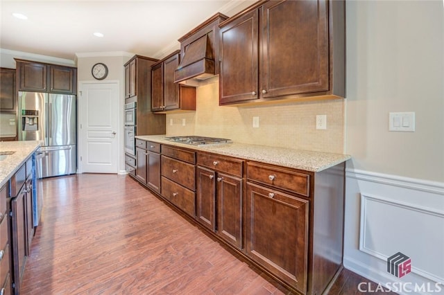 kitchen featuring dark hardwood / wood-style floors, crown molding, stainless steel appliances, dark brown cabinets, and light stone counters