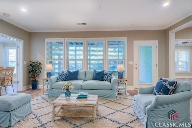 living room with plenty of natural light, crown molding, and light hardwood / wood-style flooring