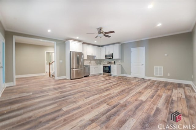 kitchen with appliances with stainless steel finishes, decorative backsplash, light hardwood / wood-style flooring, and white cabinetry