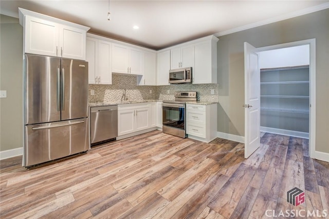 kitchen featuring white cabinets, appliances with stainless steel finishes, light hardwood / wood-style floors, sink, and light stone counters