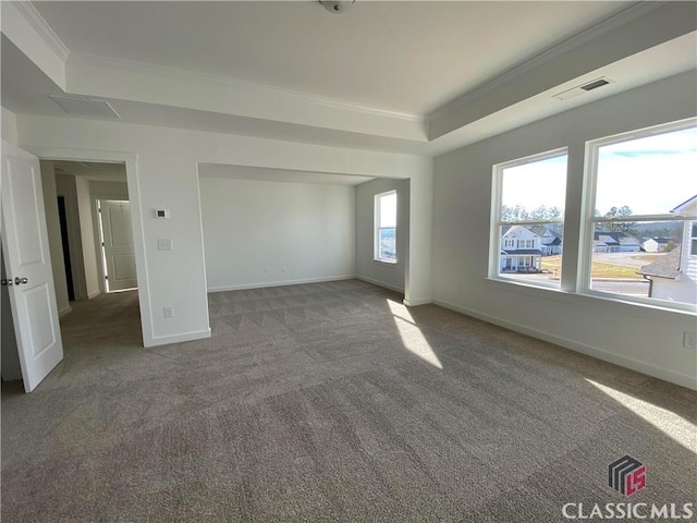 unfurnished room with a raised ceiling, crown molding, and dark carpet