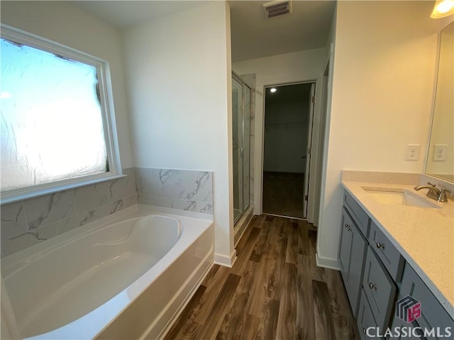 bathroom with wood-type flooring, vanity, and independent shower and bath