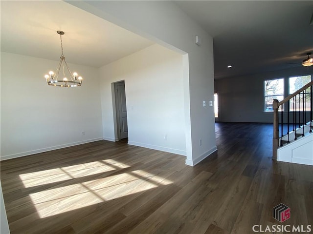 spare room with dark hardwood / wood-style floors and ceiling fan with notable chandelier