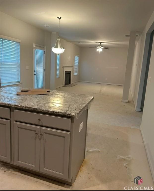 kitchen with ceiling fan, gray cabinetry, and light stone countertops