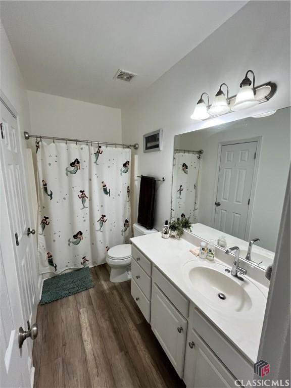 bathroom with vanity, hardwood / wood-style flooring, curtained shower, and toilet