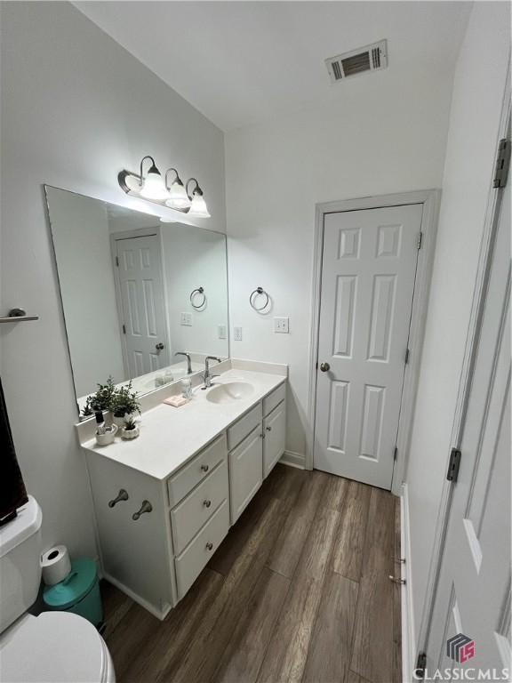 bathroom featuring wood-type flooring, toilet, and vanity