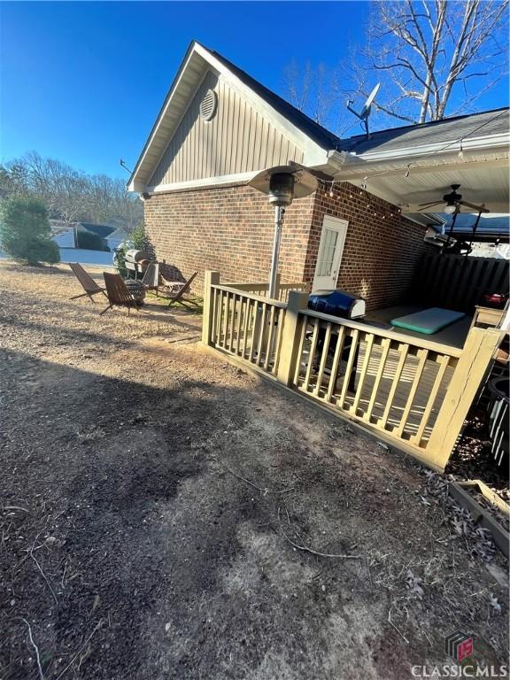 view of side of property featuring ceiling fan and a wooden deck