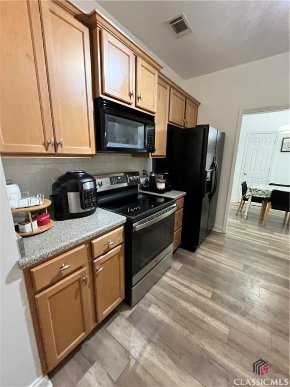 kitchen featuring black appliances, light wood-type flooring, and tasteful backsplash