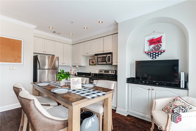 kitchen featuring dark wood-type flooring, appliances with stainless steel finishes, crown molding, and white cabinetry