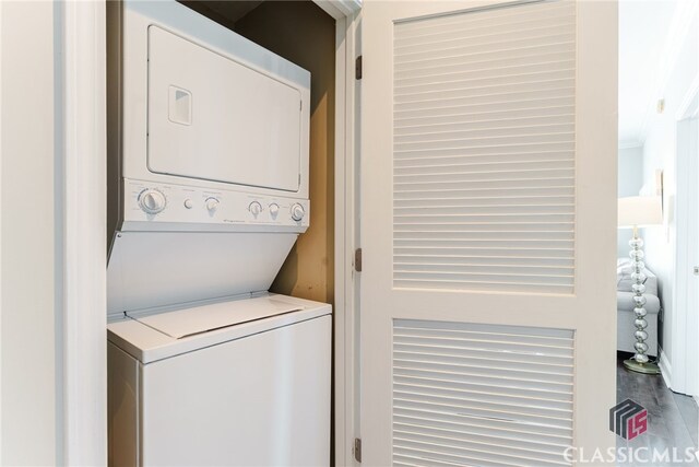 clothes washing area featuring stacked washer / drying machine and hardwood / wood-style flooring