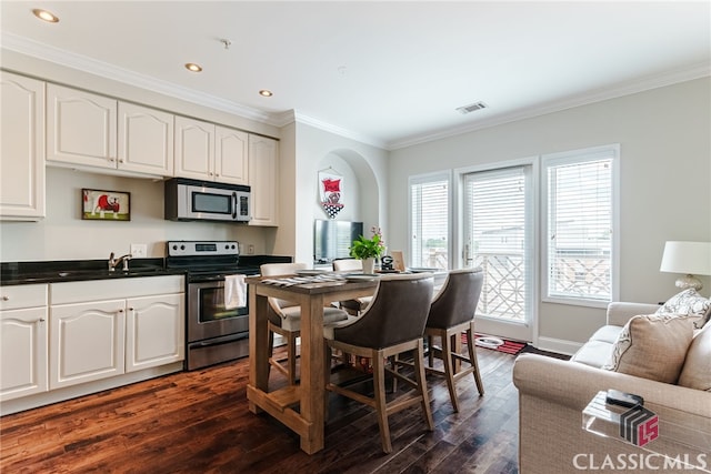 kitchen with appliances with stainless steel finishes, dark hardwood / wood-style flooring, and white cabinets