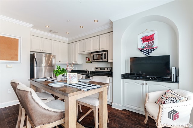 kitchen featuring dark wood-type flooring, appliances with stainless steel finishes, crown molding, and white cabinetry