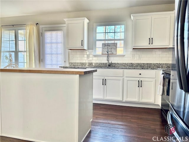 kitchen with dark hardwood / wood-style floors, decorative backsplash, white cabinetry, stainless steel fridge, and butcher block counters