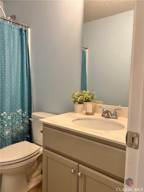 bathroom featuring toilet, vanity, and a shower with shower curtain